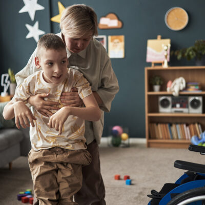 Nurse helping disabled young teenager in living room