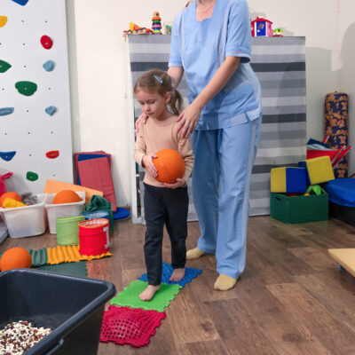 Occupational Therapist assists female child on a sensory mat